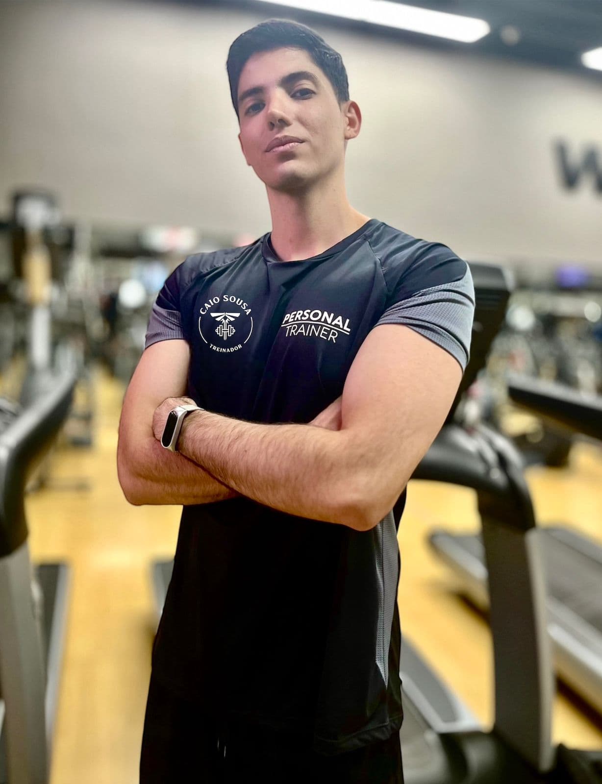 Caio Sousa, personal trainer, em pé na academia